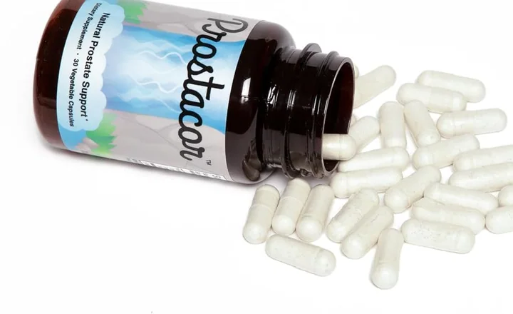 Prostacor bottle on its side with white capsules spilled out